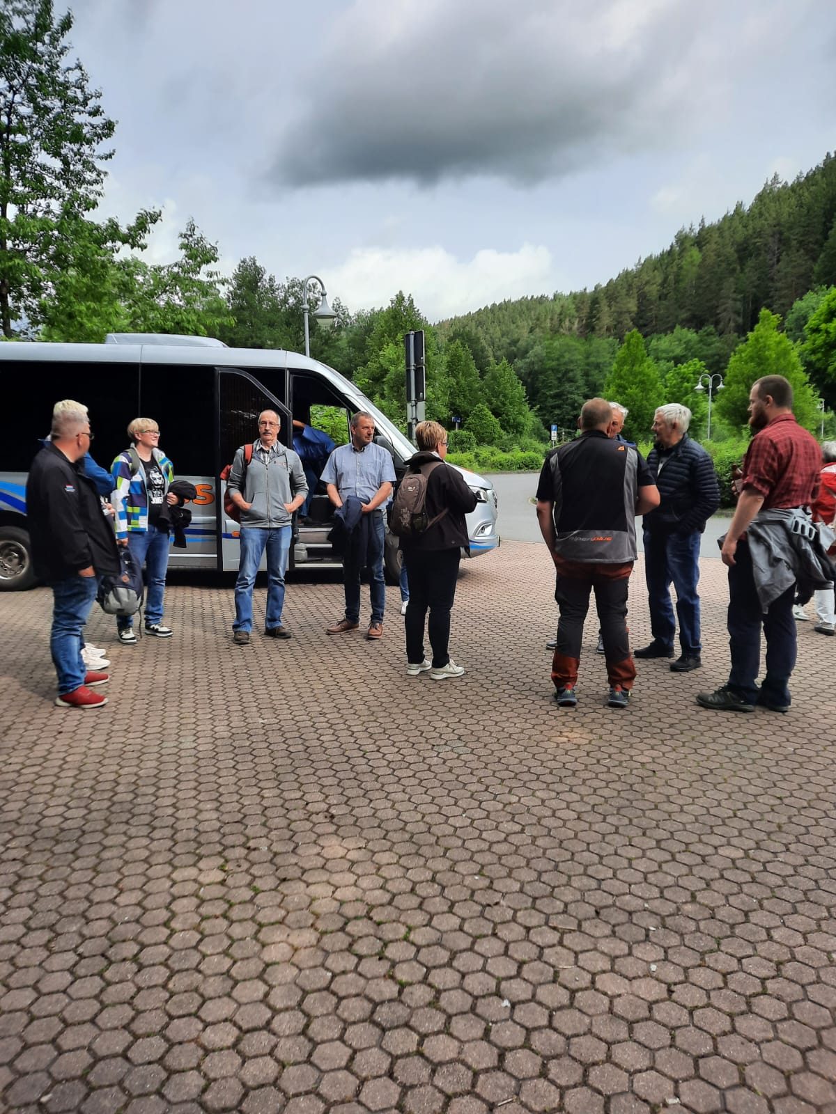 Ausflügler stehen am Reisebus beisammen